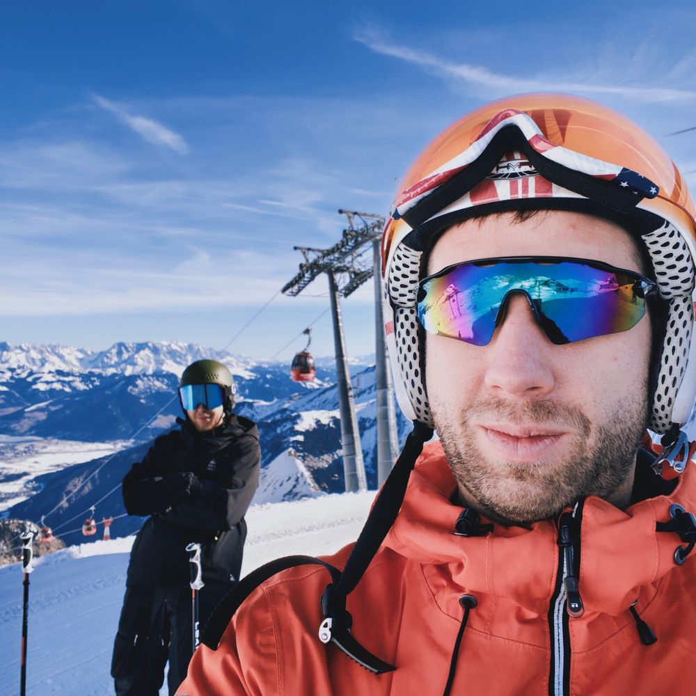 Selfie na stoku, w tle wyciąg i ośnieżone szczyty